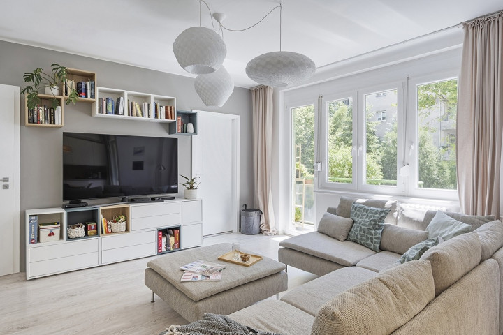 A cozy living room featuring a couch, coffee table, and bookshelves, illuminated by a stylish white C pendant light.