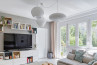 A comfortable living room showcasing a couch, coffee table, and bookshelves, beautifully lit by a white C pendant light fixture.